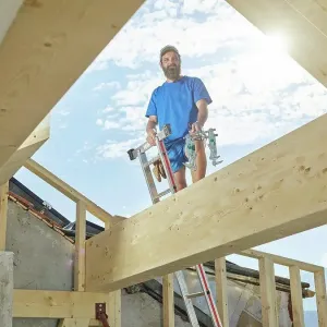 Young man standing on ladder at construction site Young man standing on ladder at construction site