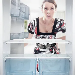 Young woman looking on empty shelf in fridge Young woman looking on empty shelf in fridge