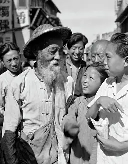 Speak Prints: 1920S 1930S Elderly Old Chinese Man With Beard Wearing Straw Coolie Hat Talking With Young People
