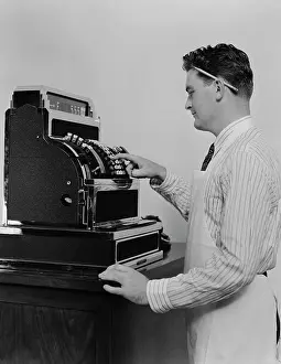 Clerk Prints: 1920S 1930S Man Wearing Apron Ringing Up Sale On Cash Register