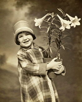 Faithful Prints: 1920s 1930s SMILING LITTLE GIRL LOOKING AT CAMERA WEARING PLAID COAT CLOCHE HAT HOLDING A POT OF EASTER LILIES