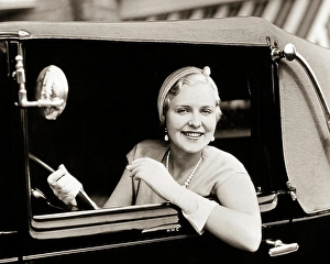 Autos Prints: 1920S 1930s SMILING WOMAN DRIVING CAR LOOKING OUT WINDOW WEARING GLOVES PEARL NECKLACE ELEGANTLY DRESSED