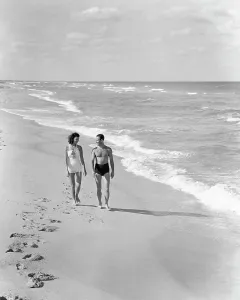 Husband Prints: 1930s 1940s COUPLE WEARING BATHING SUITS WALKING TALKING TOGETHER ON BRIGHT WARM SUNLIT SEASHORE OCEAN BEACH SAND