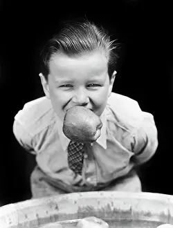 Oldtime Prints: 1930s BOY BOBBING FOR APPLES WITH AN APPLE IN HIS MOUTH LOOKING AT CAMERA