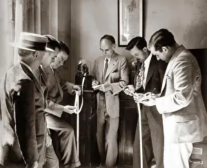Consult Prints: 1930S Brokers Businessmen Reading Ticker Tape As It Comes Out Of Glass Domed Machine