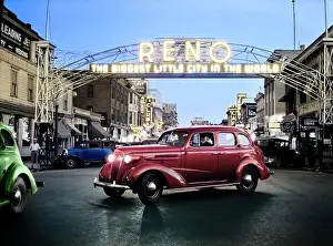 Autos Prints: 1930s CARS DRIVING AT NIGHT UNDER MAIN STREET NEON ARCH SIGN EXCLAIMING THE BIGGEST LITTLE CITY IN THE WORLD RENO