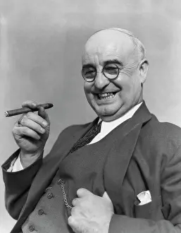 Smoking Prints: 1930S Elderly Businessman In 3-Piece Suit & Glasses Leaning Back Smiling With Cigar In Hand