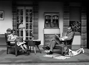 Small Group Of People Prints: 1930S Man Father Reading Newspaper Boy Girl Reading Comics In Living Room