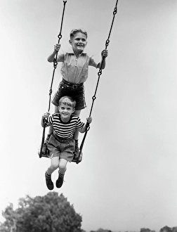 People Children Prints: 1930S Two Smiling Boys Sitting Standing On Playground Swing