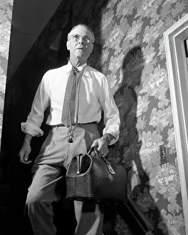 Doctors Prints: 1940s 1950s DOCTOR WITH BAG AND STETHOSCOPE WALKING DOWN STAIRS IN HOME AFTER MAKING AN EMERGENCY HOUSE CALL