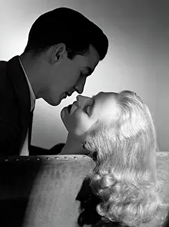 Spouses Prints: 1940S 1950S Movie Star Studio Style Romantic Couple Embracing On Sofa About To Kiss Husband Silhouette Wife Long Blond