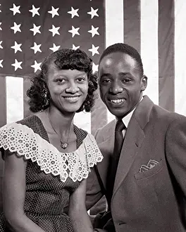 Expressions Prints: 1940s 1950s SMILING AFRICAN AMERICAN COUPLE PORTRAIT LOOKING AT CAMERA IN FRONT OF UNITED STATES FLAG