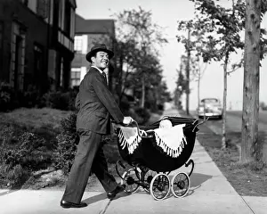 Parenting Prints: 1940S 1950S Smiling Father In Suit & Hat Pushing Baby In Carriage Down Sidewalk