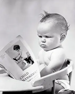 Expressions Prints: 1940s FROWNING FLUMMOXED DISAPPROVING GRUMPY BABY BOY SITTING IN CHAIR READING A PUBLICATION TITLED CHILD MANAGEMENT