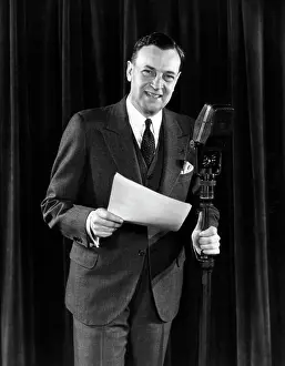 Communications Prints: 1940S Man Announcer Emcee Smiling Standing With A Script In One Hand The Other Holding The Microphone Stand Looking At