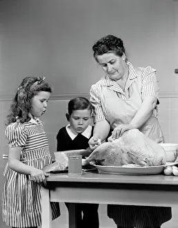 Small Group Of People Prints: 1940S Mother Son Daughter In Kitchen Stuffing Turkey For Thanksgiving Dinner