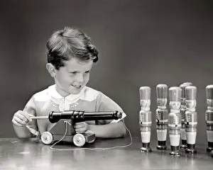 Cork Prints: 1940s SMILING BOY ABOUT TO SHOOT CORK POP GUN TOY CANNON INTO ROW OF TOY WOODEN SOLDIERS