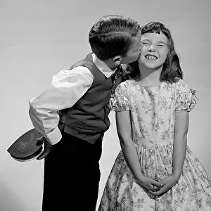 Valentines Prints: 1950S 1960S Boy In Vest & Bow Tie Holding Valentine Candy Kissing Cheek Of Girl Making A Face