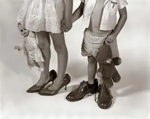 Parenting Prints: 1950S 1960S Close-Up Of Little Girl & Boy From Neck Down Wearing Parents Shoes