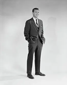 People Adults Prints: 1950S 1960S Portrait Smiling Man Standing With Hands In Pockets Wearing Suit And Tie