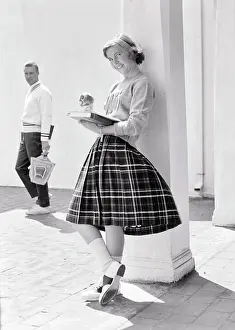 Students Prints: 1950s 1960s TEEN GIRL LEANING AGAINST COLUMN EATING APPLE READING BOOK LOOKING AT CAMERA SMILING AS POTENTIAL BOYFRIEND