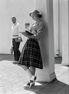 Skirt Prints: 1950S 1960S Teen School Girl Plaid Skirt Leaning Against Column Eating Apple Reading Book As Boy Walks By In Background