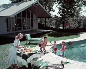 Nourishment Prints: 1950S Family Of 4 Backyard Swimming Pool House Mom Serving Food Meal At Table By Grill Dad Boy Girl Summer Lawn