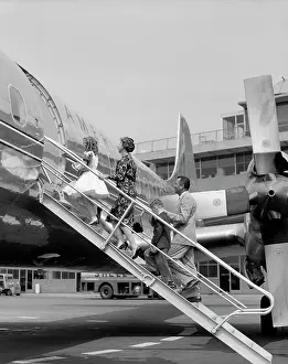 Small Group Of People Prints: 1950S Family Father Mother Daughter Son Boarding Propeller Airliner By Climbing Gangway Stairs At Airport