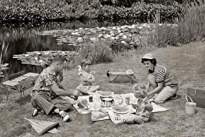 Dads Prints: 1950s FAMILY MOTHER FATHER AND TWO DAUGHTERS HAVING A SUMMER PICNIC BY POND