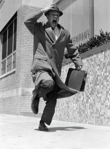 Runner Prints: 1950S Frantic Man Running Down Street Holding Hat On With Hand Carrying Briefcase Wearing Top Coat Commuter Businessman