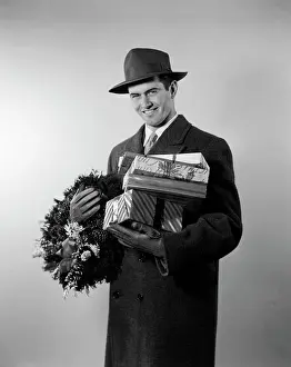 Gloves Prints: 1950S Smiling Young Man In Hat Coat And Gloves Holding Christmas Wreath And Wrapped Gifts