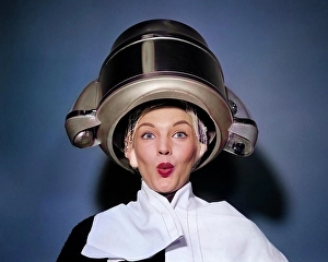 People Adults Prints: 1950s SURPRISED WOMAN SITTING UNDER HAIR DRYER WITH TOWEL ON SHOULDERS AND HAIR NET LOOKING AT CAMERA