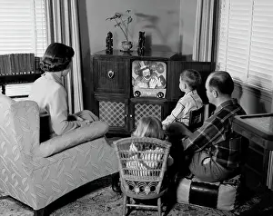 Parenting Prints: 1950S Back View Of Family Of 4 Gathered Around Tv Set Watching Clown With Balloons
