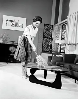 Cleaning Prints: 1950S Woman Wearing A White Blouse & Plaid Skirt Dusting With A Feather Duster A Glass Top Coffee Table