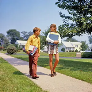 Skirt Prints: 1960s 1970s BOY GIRL ON SIDEWALK WALKING HOME FROM OR TO SCHOOL TALKING CARRYING BOOKS GIRL WEARING FAUX SNAKESKIN MINI