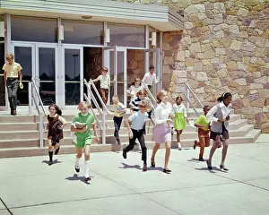 Diverse Prints: 1960s 1970s GROUP OF ETHNICALLY DIVERSE KIDS RUNNING OUT OF SCHOOL BUILDING AT END OF DAY OR END OF SCHOOL YEAR SUMMER