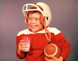 Nourishment Prints: 1960S Boy Drinking Milk Wearing Football Helmet Red Jersey Holding Ball