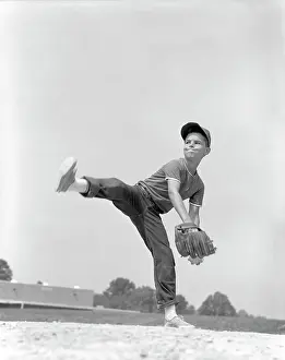 Determined Prints: 1960S Boy Wearing Baseball Cap Tee Shirt Blue Jeans And Determined Expression In Wind-Up To Deliver Pitch