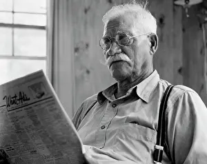 Communications Prints: 1960S Close-Up Of Elderly Man With Mustache Wearing Suspenders & Round Glasses Reading Newspaper