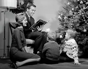 Maternal Prints: 1960S Family Father Mother Two Sons Smiling Sitting By Christmas Tree In Living Room Reading A Book