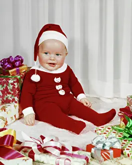 Oldtime Prints: 1960s HAPPY BABY WEARING SANTA CLAUS FOOTED PAJAMAS SITTING AMONG WRAPPED CHRISTMAS PRESENTS