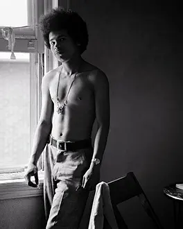 Expressions Prints: 1960s IMPOVERISHED YOUNG SHIRTLESS AFRICAN-AMERICAN MAN STANDING BY WINDOW SMOKING LOOKING AT CAMERA ANGRY FACIAL