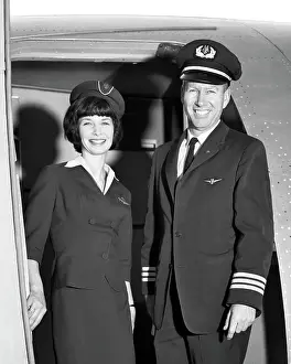 Mid Adultman Prints: 1960s MAN CO-PILOT AND WOMAN FLIGHT ATTENDANT STANDING SMILING IN DOOR OF AIRPLANE LOOKING AT CAMERA