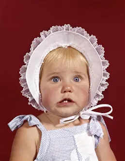 Tooth Prints: 1960S Portrait Baby Girl Wearing Bonnet And Blue Gingham Dress Showing Two Front Teeth Looking At Camera