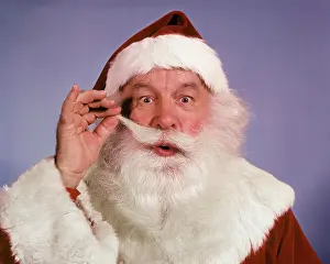 Grownup Prints: 1960s PORTRAIT SANTA CLAUS TWIRLING THE END OF HIS MUSTACHE LOOKING AT CAMERA