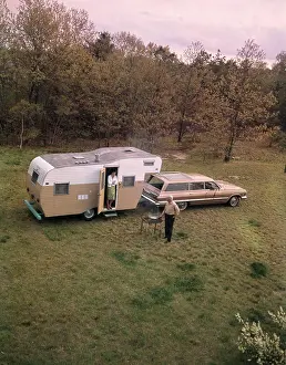 Elder Prints: 1960S Senior Man Grilling Woman Standing In Door Of Camper Hitched To Station Wagon