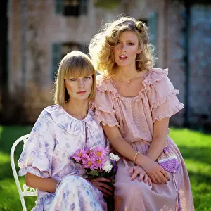 Expressions Prints: 1970s 1980s TWO BLONDE WOMEN WEARING RUFFLED DRESSES IN PASTEL COLORS SITTING OUTDOORS LOOKING AT CAMERA