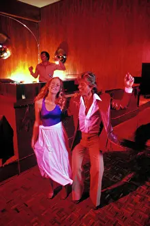 Skirt Prints: 1970s BLONDE COUPLE ON DISCO DANCE FLOOR DOING THE HUSTLE WOMAN WEARING SPANDEX TOP MAN IN LEATHER JACKET DJ IN