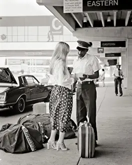 Traveling Prints: 1970s BLONDE WOMAN CHECKING BAGS CURBSIDE WITH AFRICAN AMERICAN AIRPORT SKYCAP
