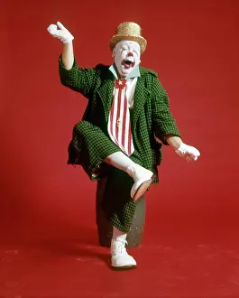 Oldtime Prints: 1970s CLOWN GREEN CHECKED BAGGY SUIT SILLY EXPRESSION SITTING ON BARREL LIFTING LEG ARMS IN AIR YAWNING